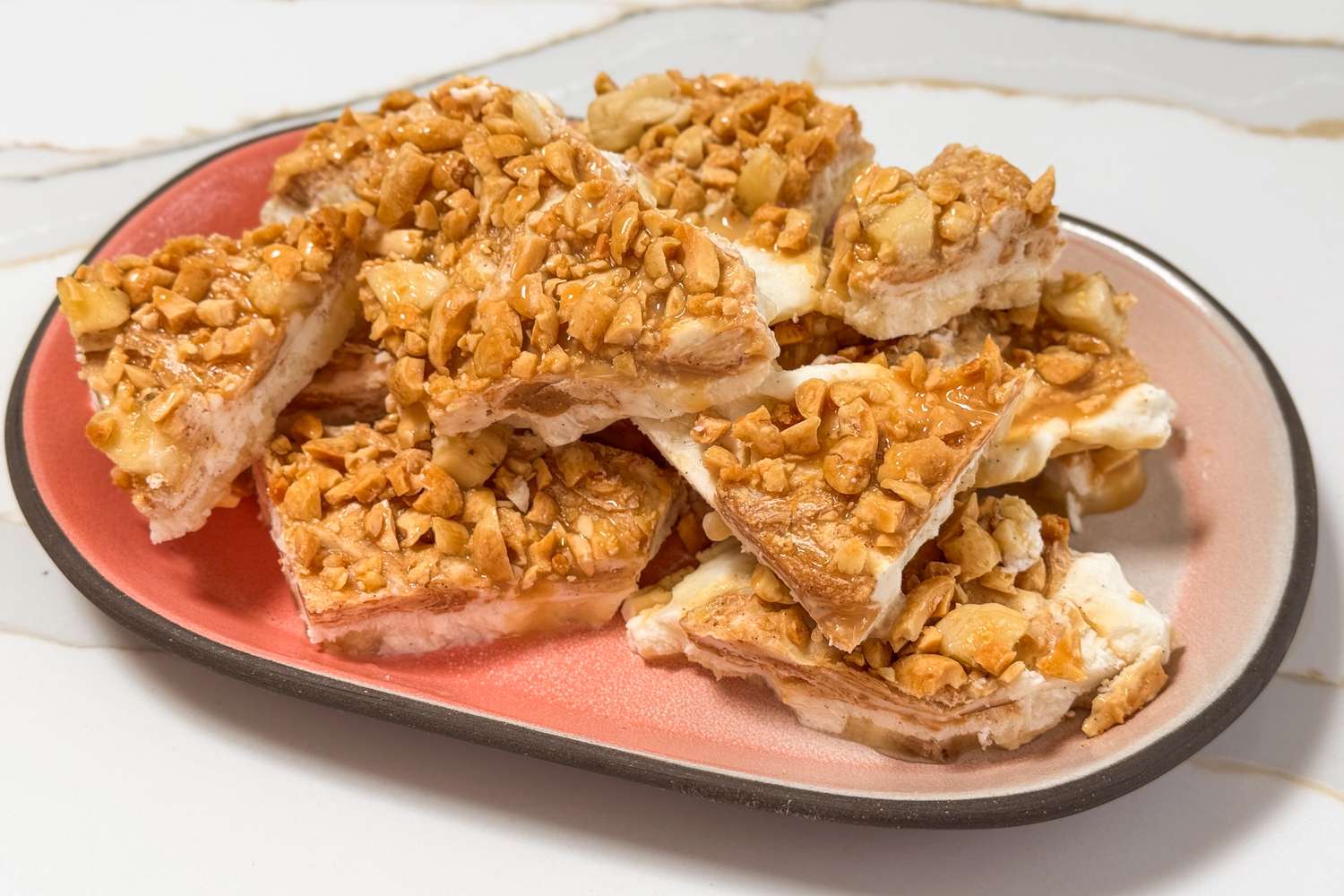 Dessert bars topped with chopped nuts arranged on a plate