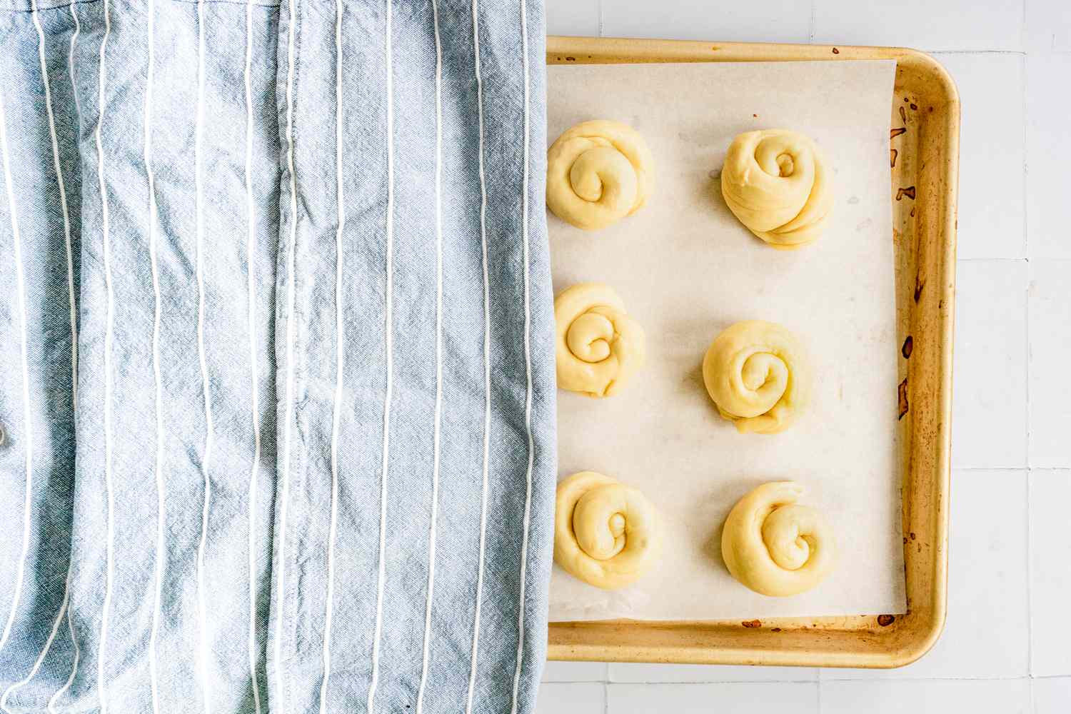 Challah Rolls Resting Under Clean Kitchen Towel in a Baking Sheet