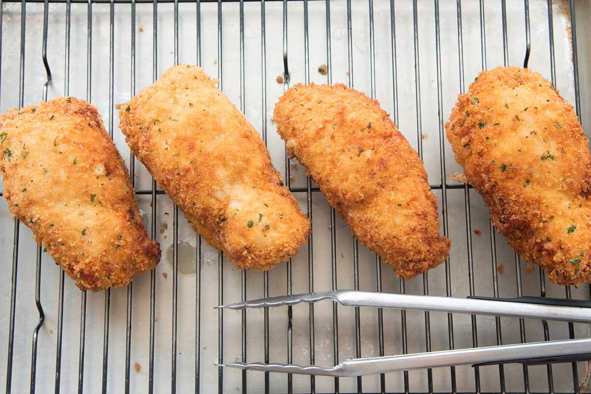 Breaded and fried chicken cordon bleu on a a bakers cooking rack.
