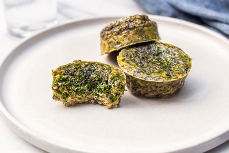 Kale and Portobello Egg Bites on a Plate with One Bitten 
