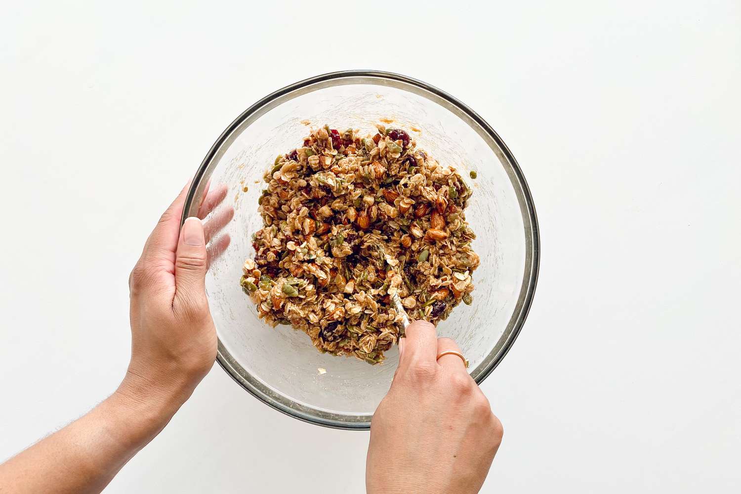 Mixing wet ingredients to dry ingredients in a bowl to make Chewy Granola Bars with Dried Fruit and Nuts.