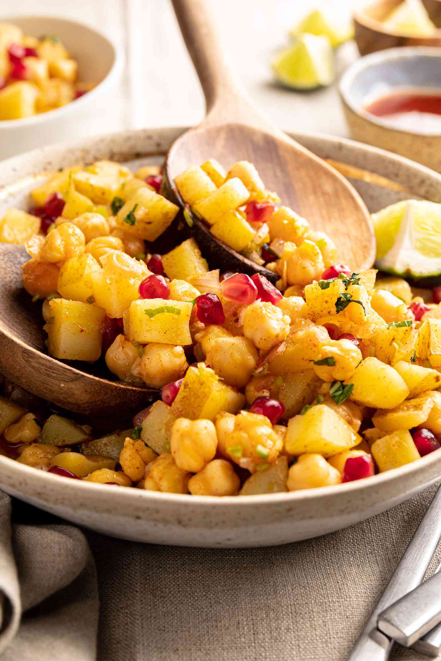Scooping Chana Chaat with wooden spoons.