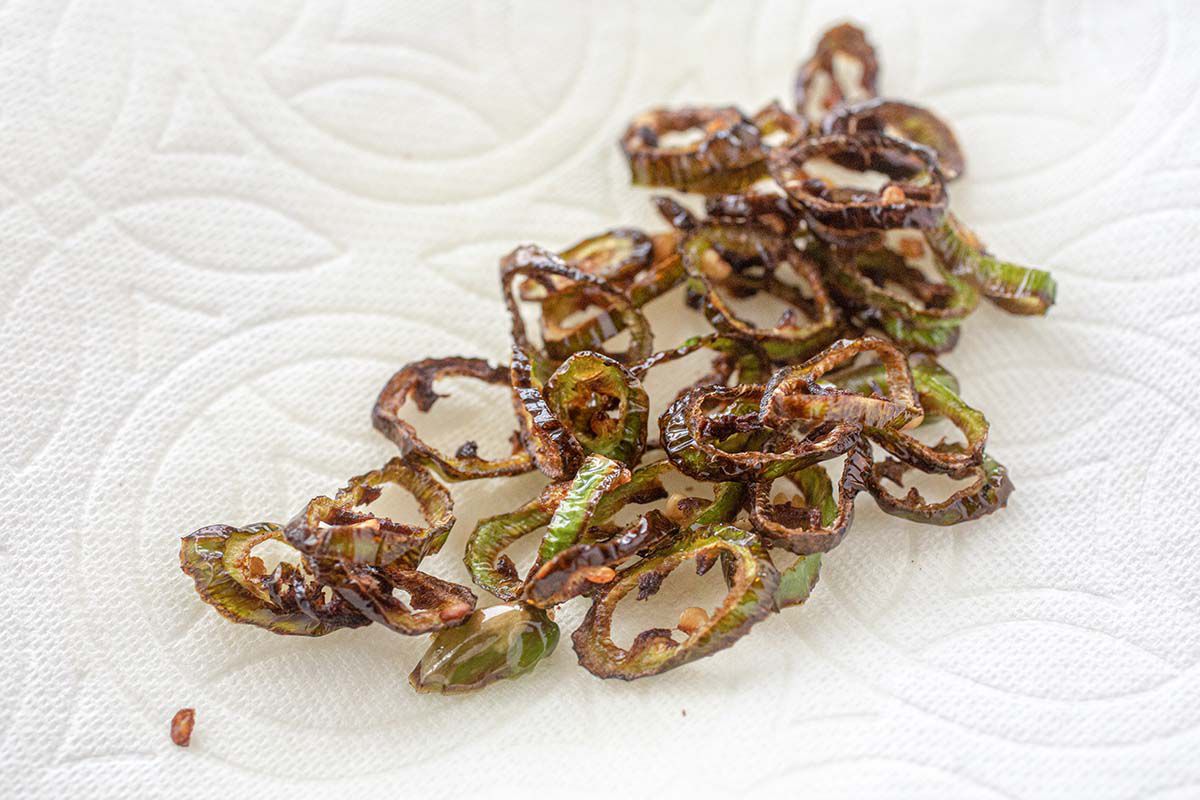Crispy sliced serrano peppers roasted and laying on a paper towel.