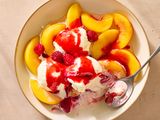 Bowl with sliced peaches, scoops of ice cream, raspberries, and red sauce
