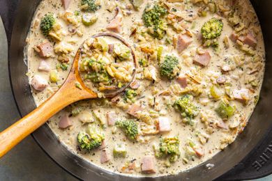 Broccoli and wild rice soup in a pot with a wooden ladle