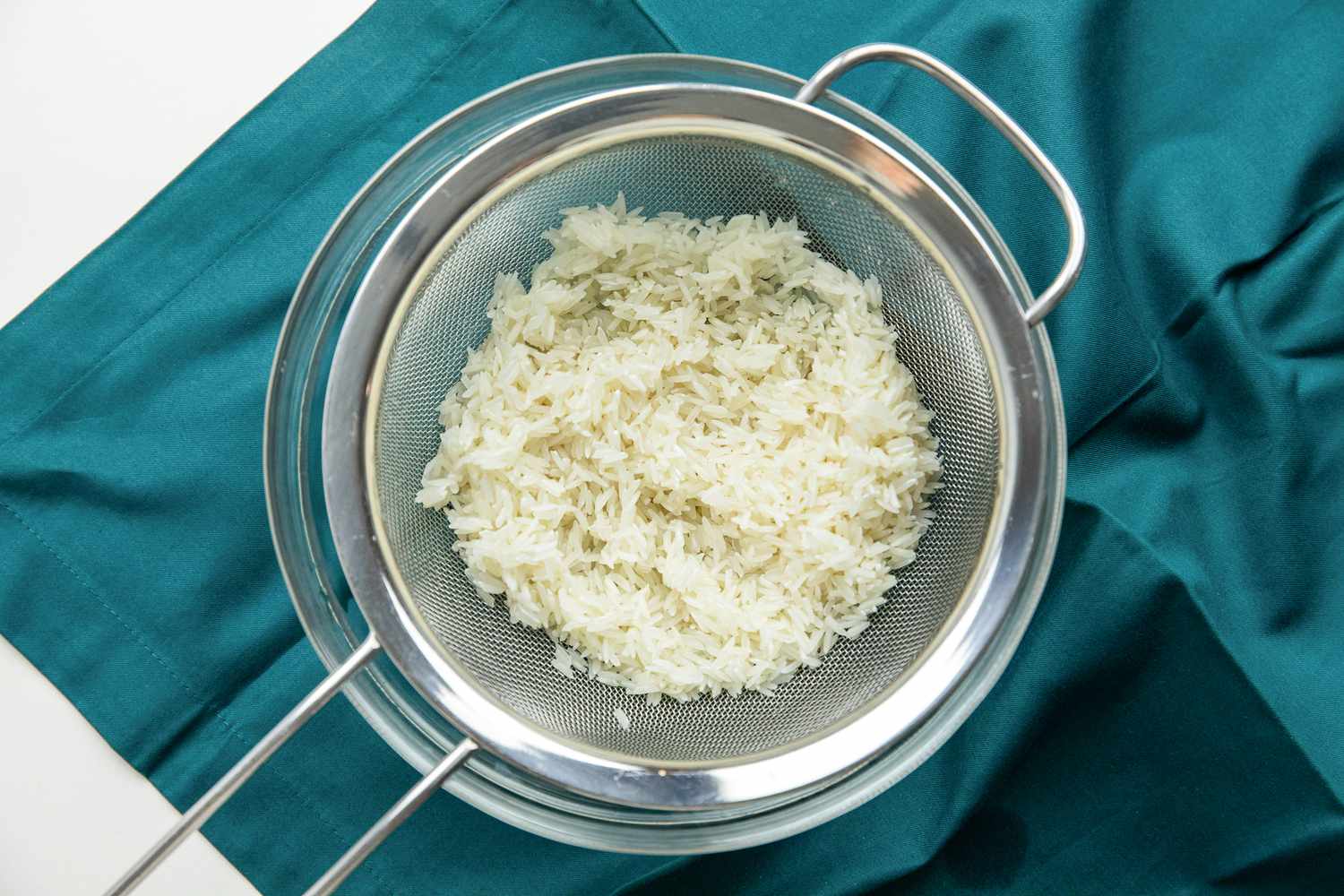 Rice in a Strainer over a Teal Kitchen Linen for Chicken Congee (Chicken Jook)