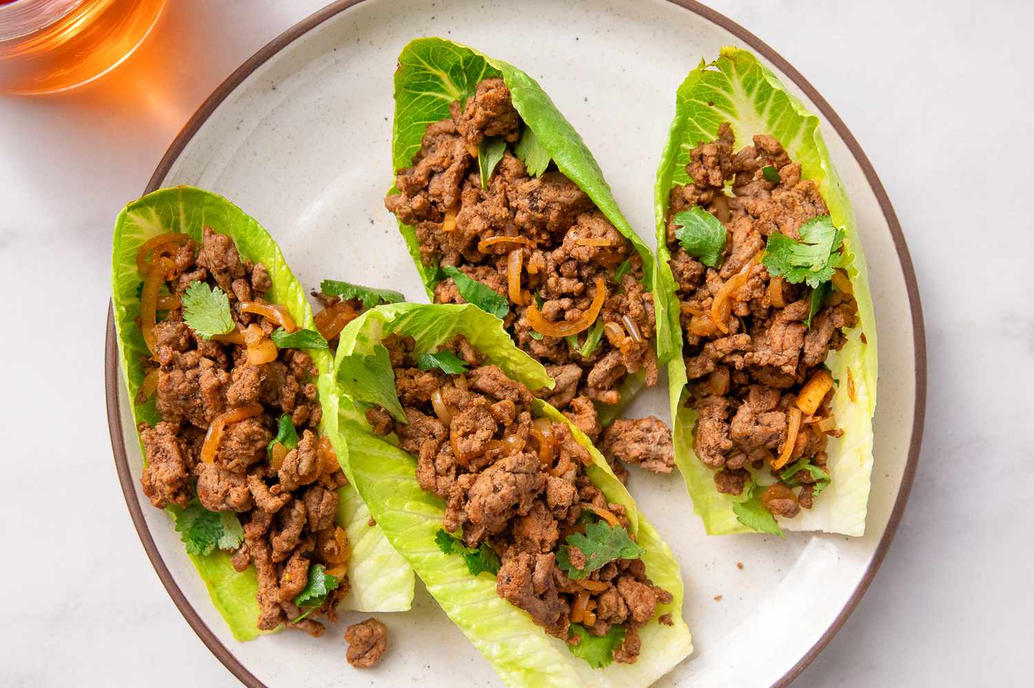 Plated lettuce cups filled with seasoned ground beef and garnishes