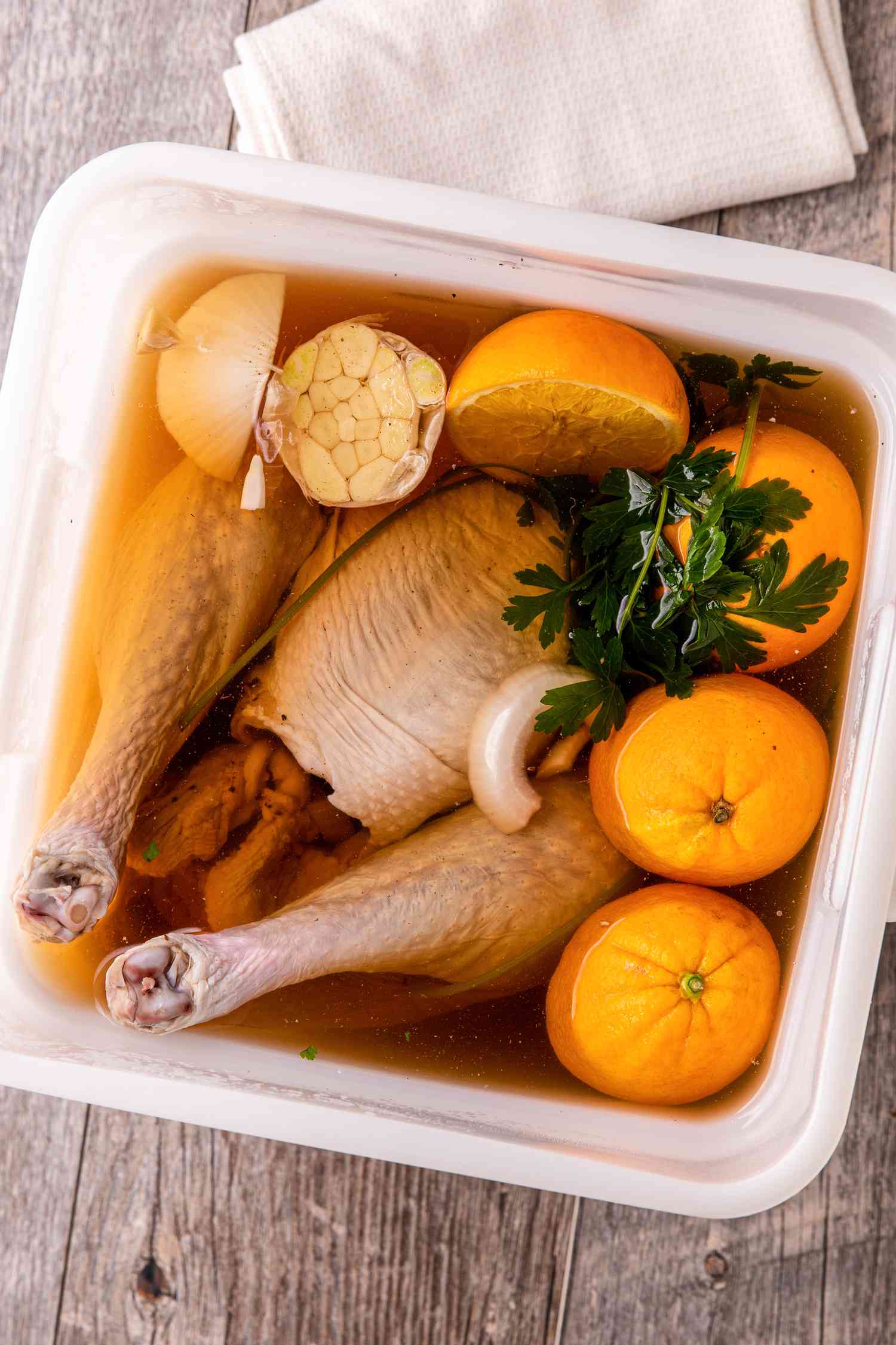 Brined whole turkey in a bucket with brining liquid.