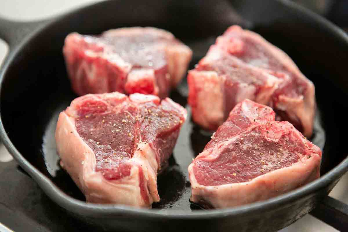 raw lamb loin chops in cast iron pan