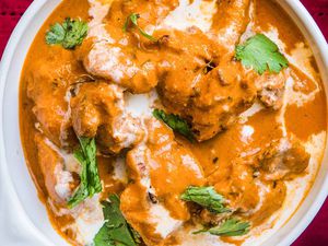 A dish of Butter Chicken garnished with cilantro leaves