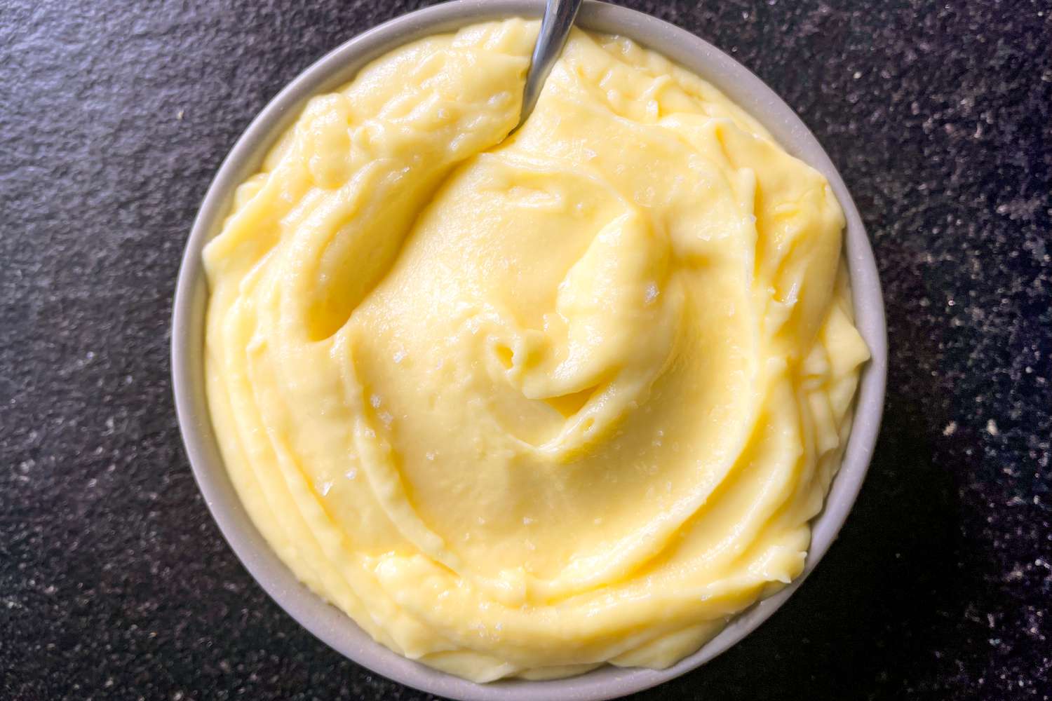 A bowl of mashed potatoes with a spoon in it