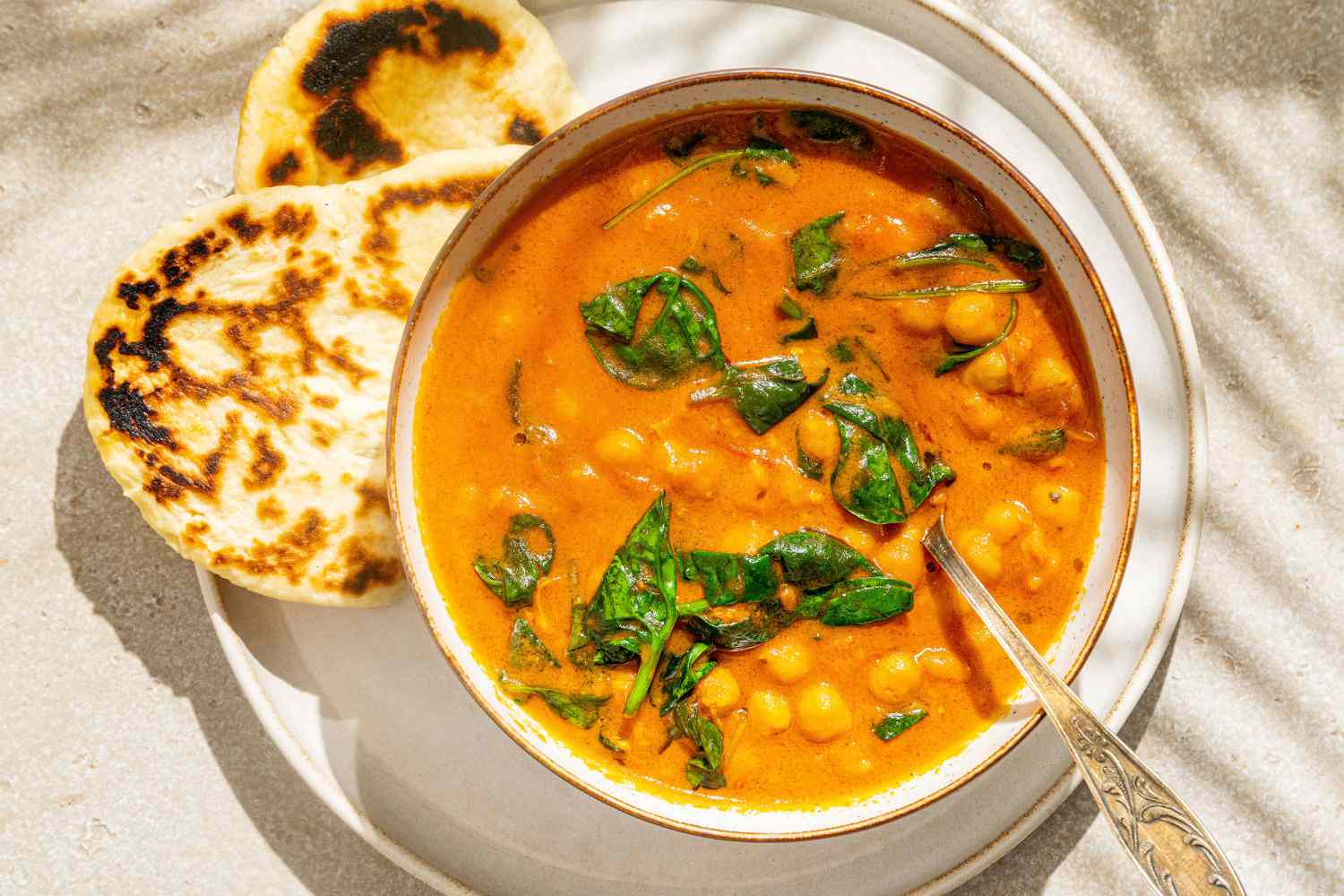 Easy Chickpea Curry in a bowl with a spoon, naan on the side