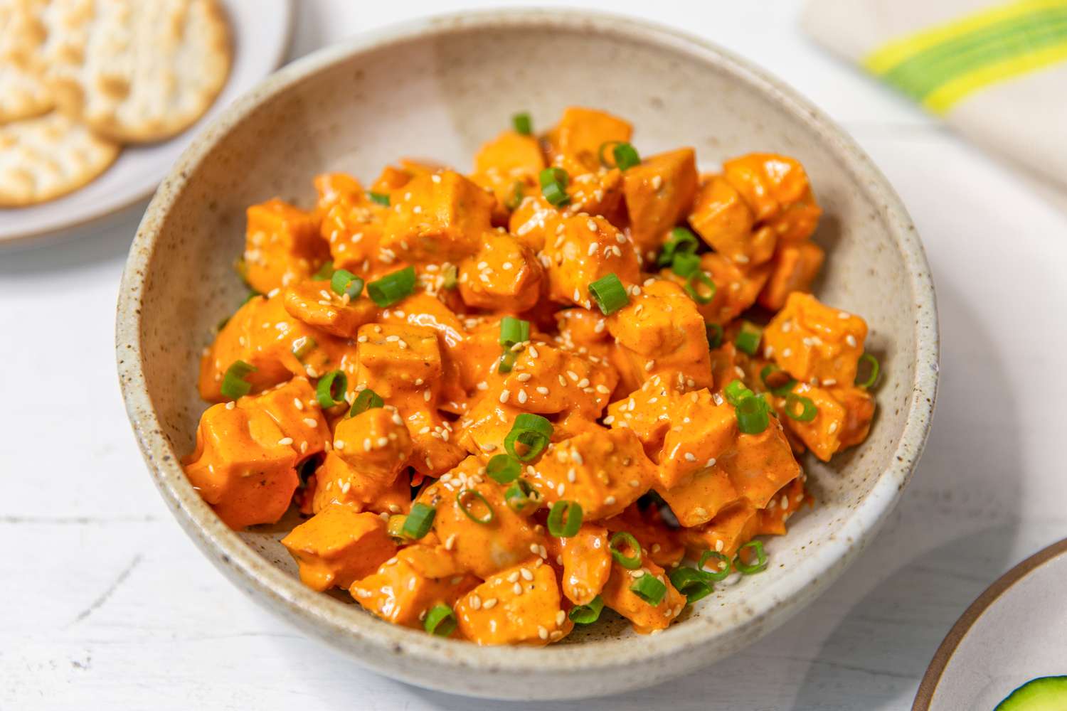 Closeup shot of a plate with gochujang chicken salad topped with chopped scallion