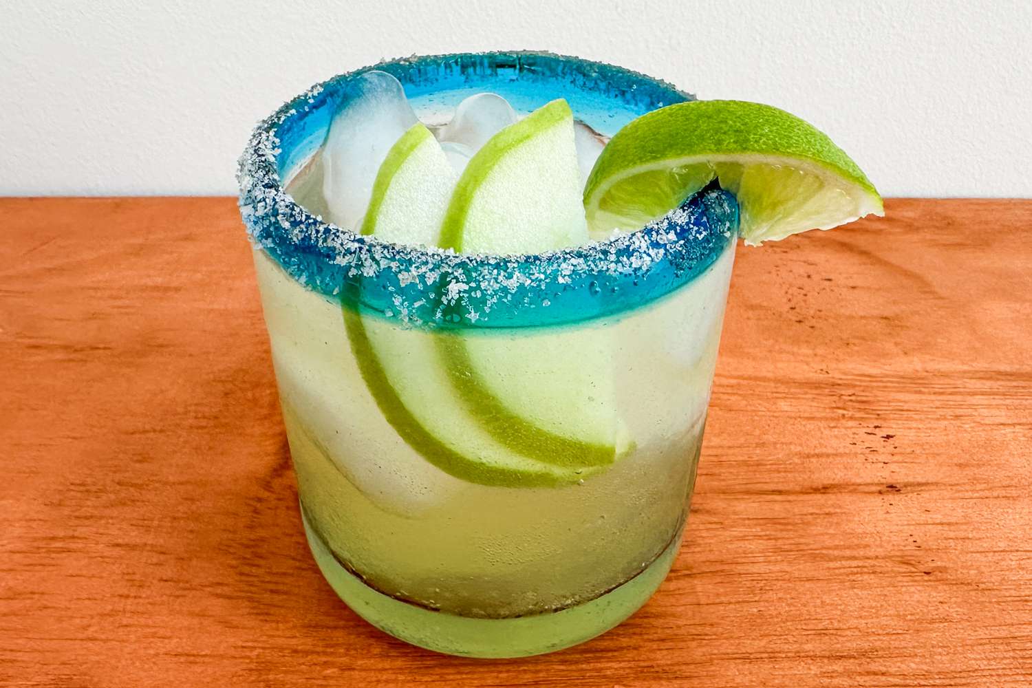 Trader Joe's apple margarita served in a single short glass garnished with a lime slice