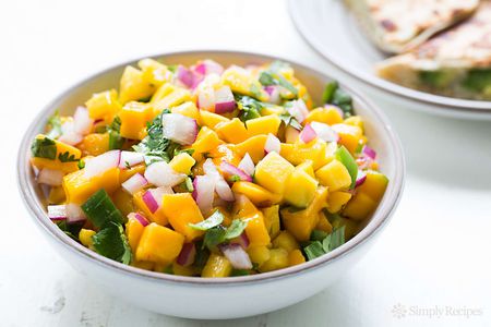 Mango Salsa in a white bowl with quesadillas in background