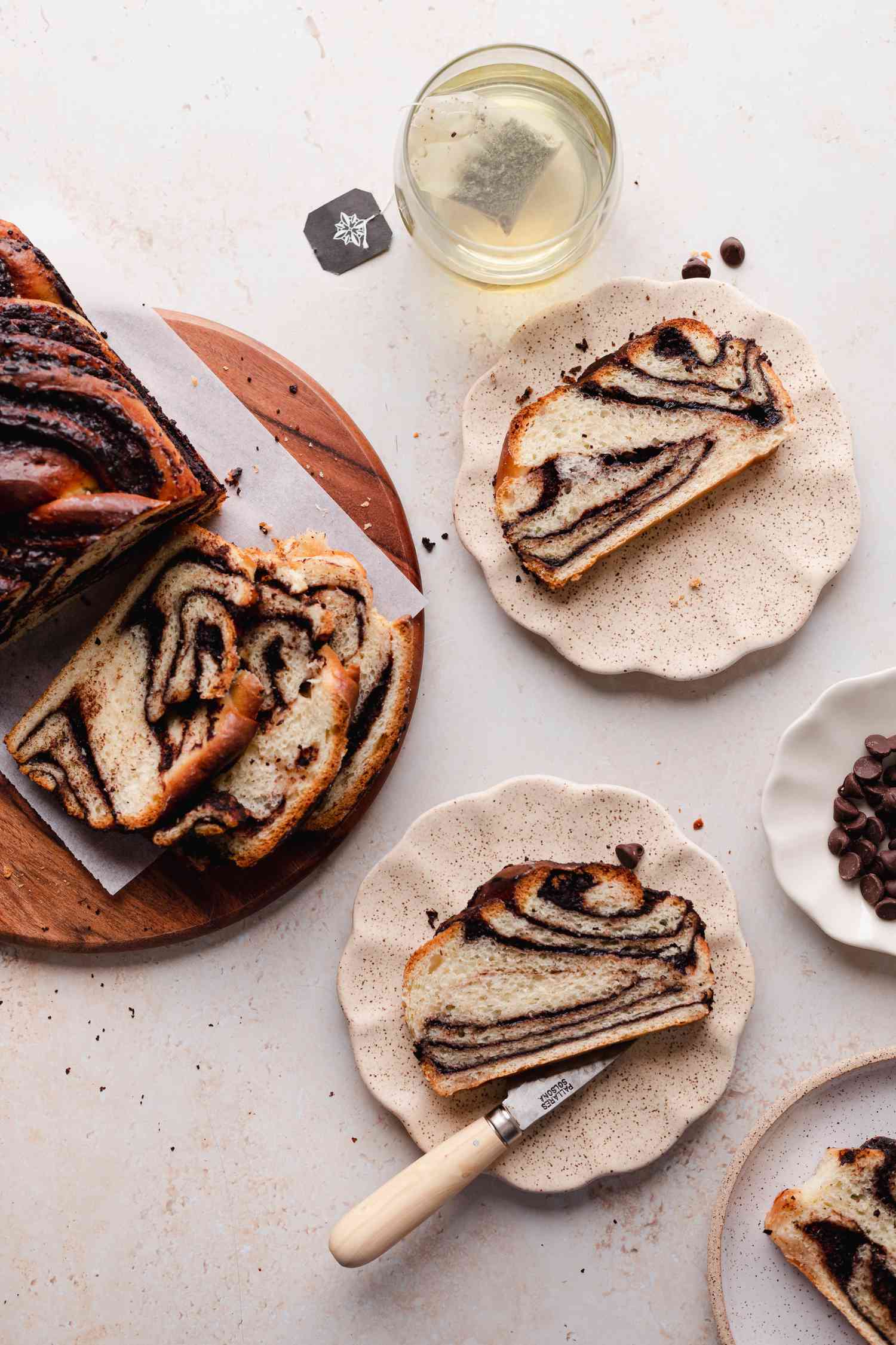 Braided chocolate babka on ruffled plates and with the loaf to the left.