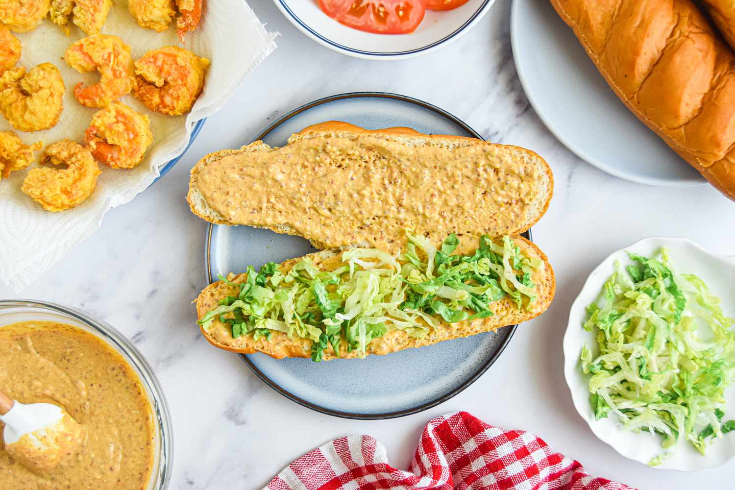 Building the Classic Shrimp Po Boy Sandwich: Remoulade and Shredded Lettuce Added Bread