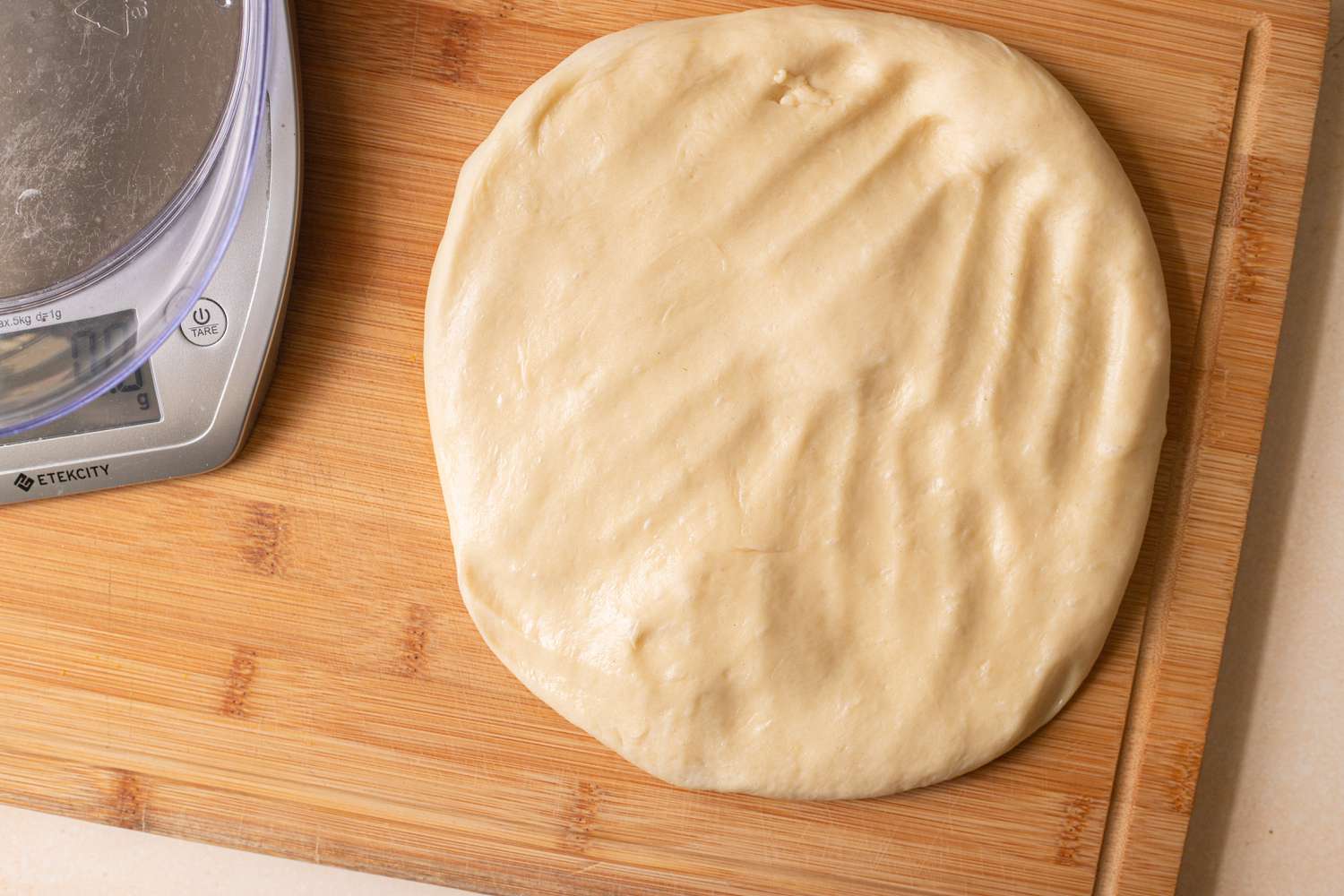 Flattening the dough into a circle to make pull apart rolls.