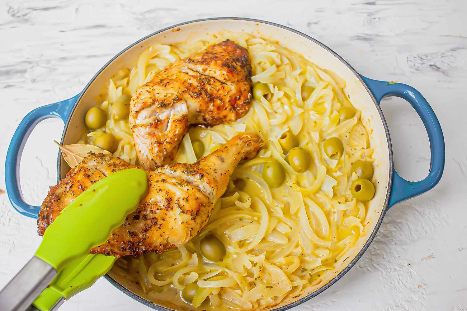 Adding chicken into onion sauce for chicken yassa recipe