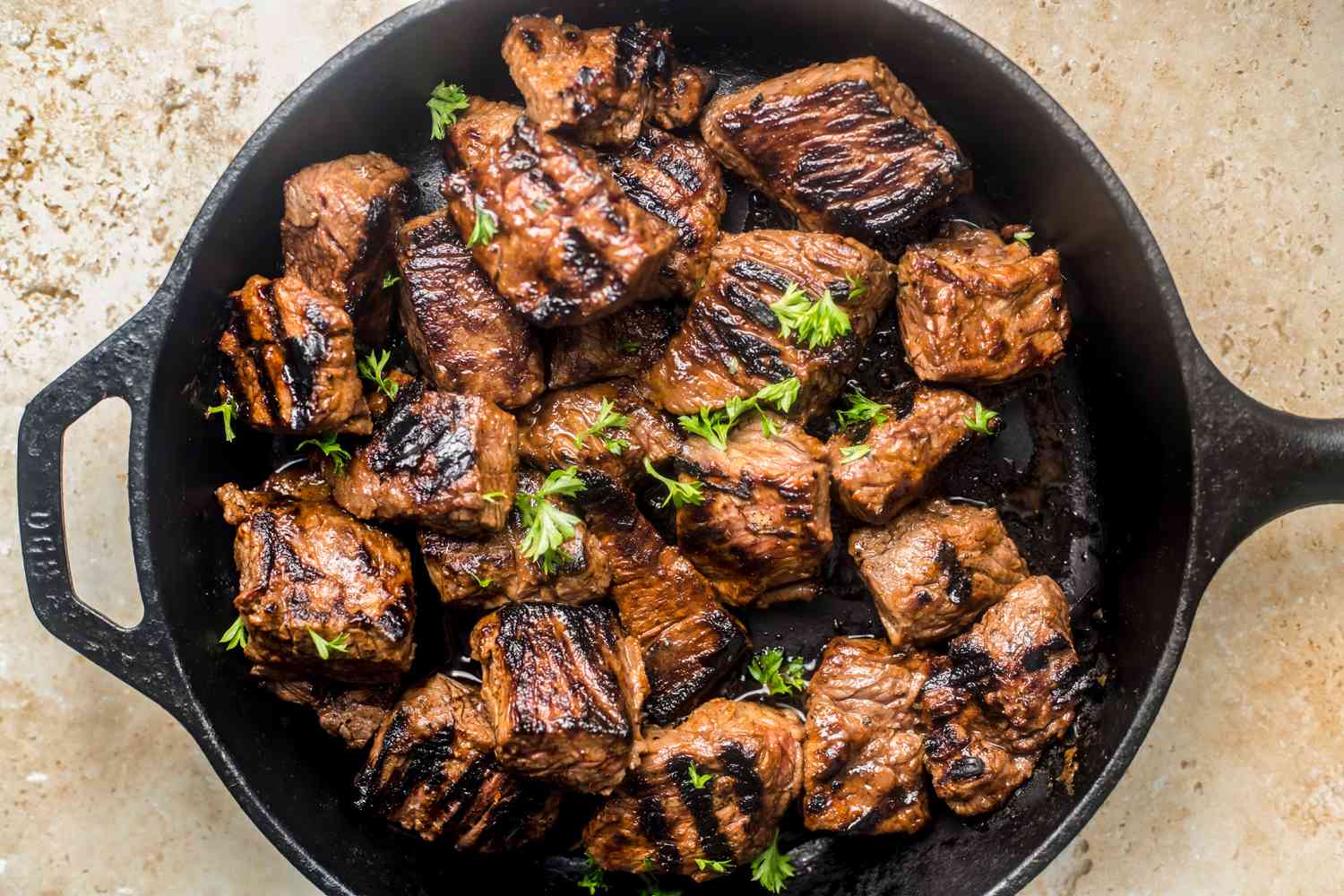 Steak tips topped with parsley on a cast iron skillet