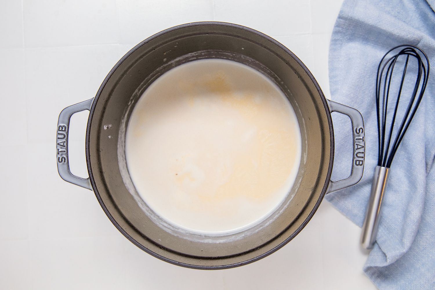 Overhead view of chicken broth and cream added to a saucepan for Marry Me Chicken Casserole recipe