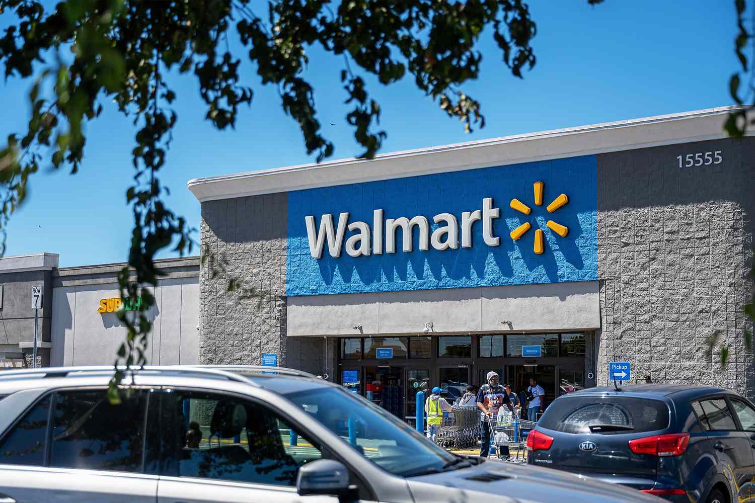 Exterior of a Walmart store with parked cars and some customers near the entrance