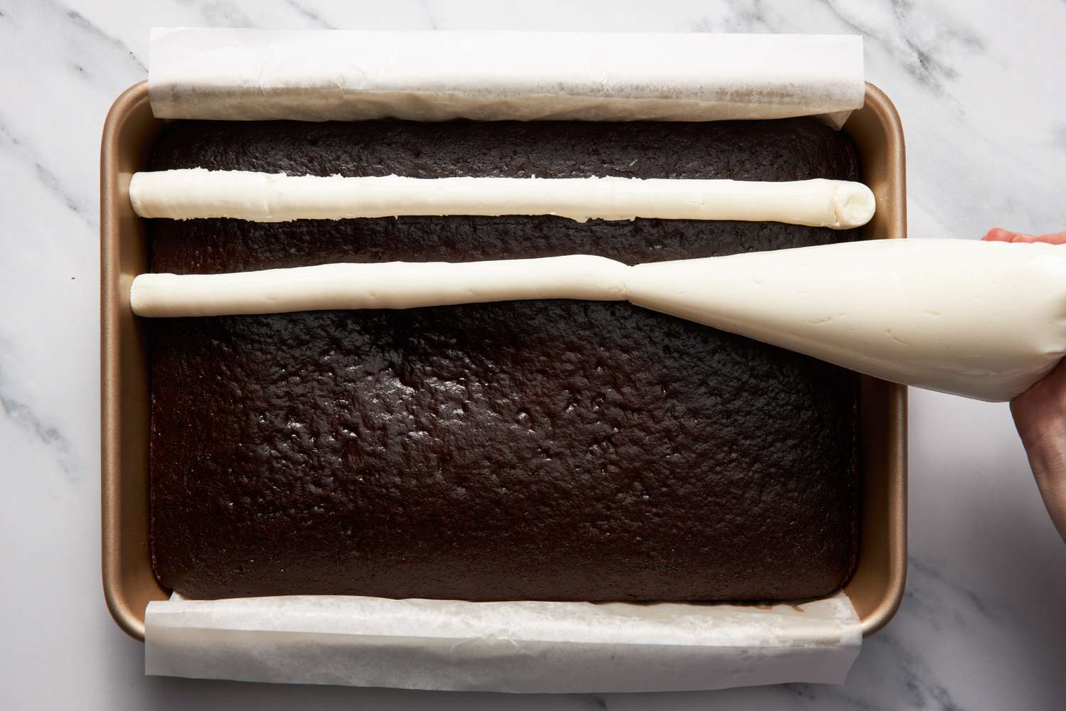 Frosting piped in long horizontal lines onto the cake for bumpy cake recipe 