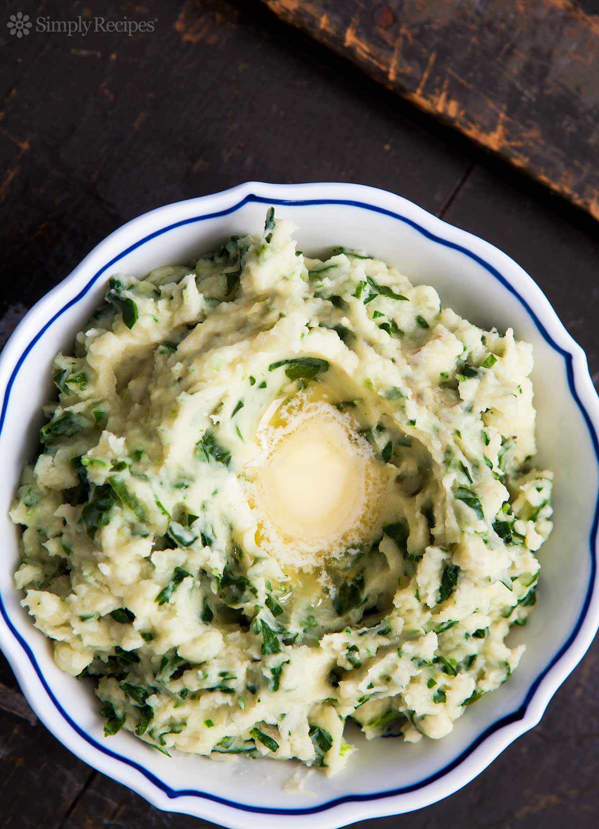 Colcannon (Irish mashed potatoes) in a white bowl topped with butter