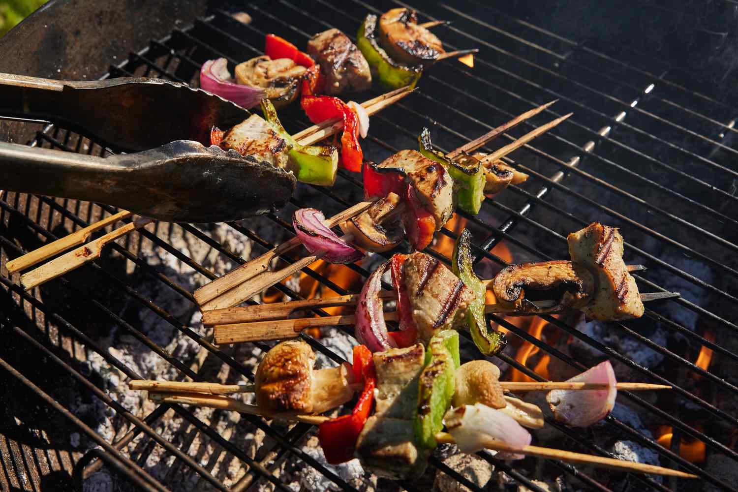 Grilled kebabs with tuna, vegetables, and tongs on a barbecue