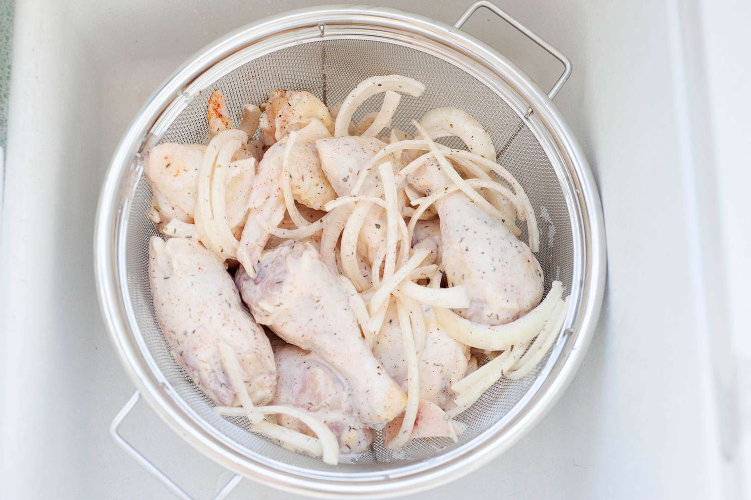 Straining chicken in a colander to make a buttermilk recipe.