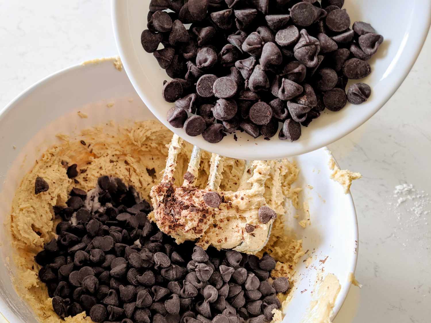 Mixing chocolate chips into a bowl of cookie dough
