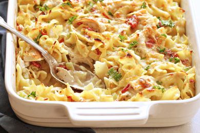 Creamy Chicken Noodle Casserole in a white baking dish with a silver spoon.