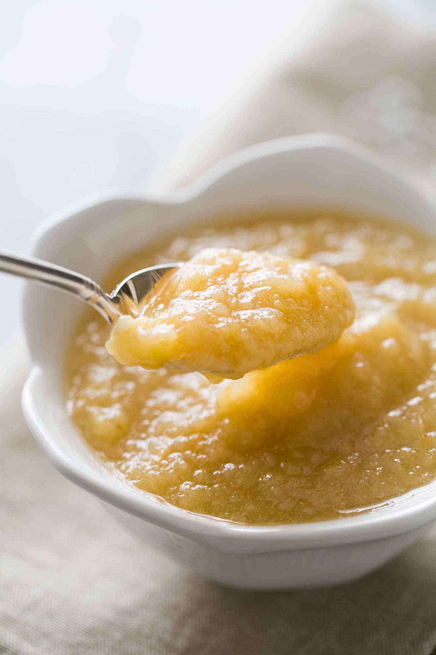A bowl of homemade Applesauce with a spoonful being taken out