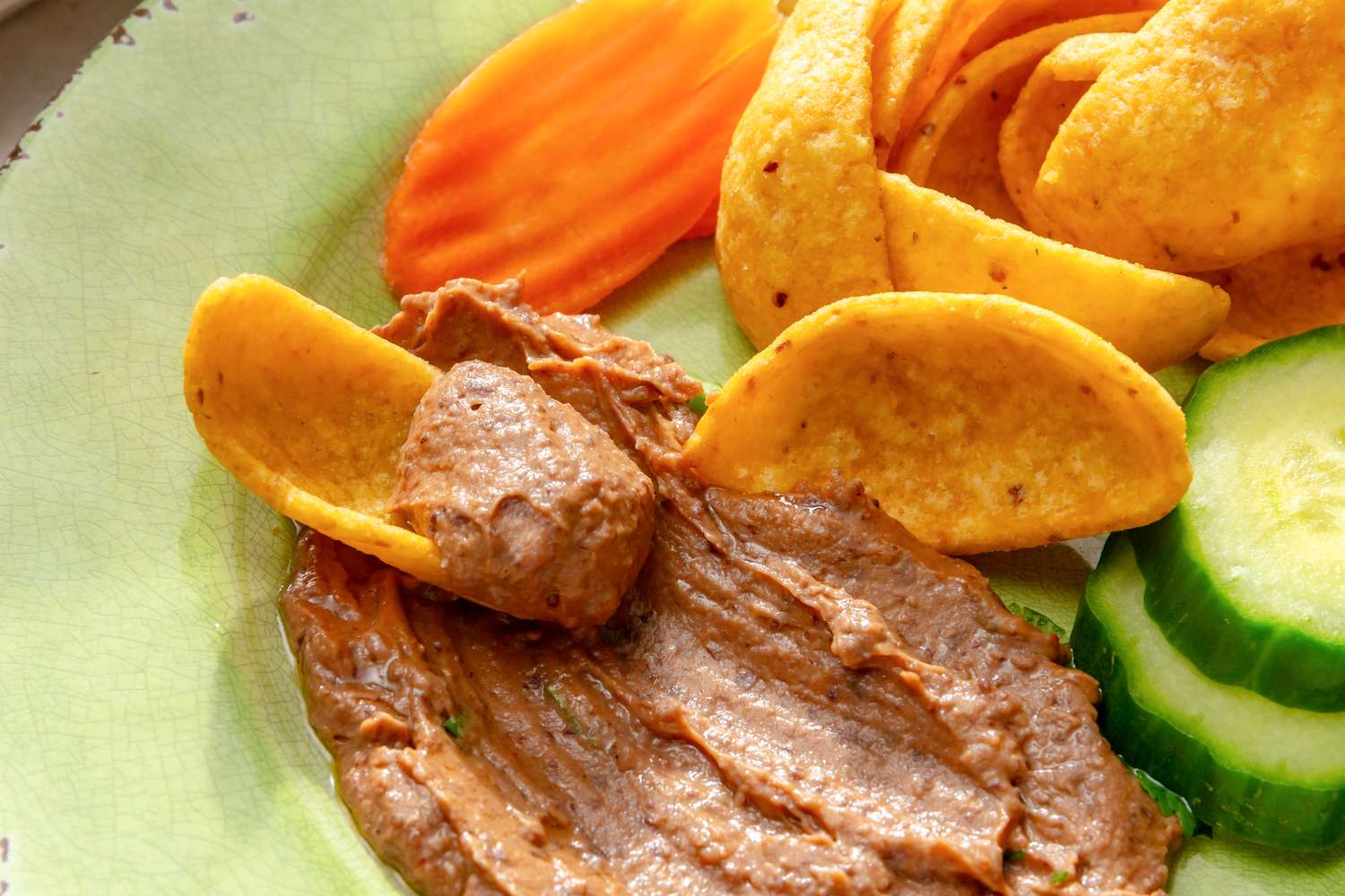 Black bean dip served with chips carrot slices and cucumber slices on a plate