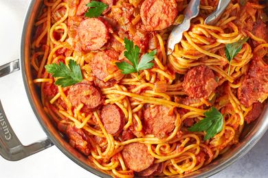 Spaghetti in tomato sauce with sausage slices in a pan