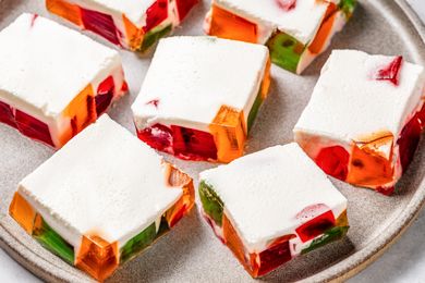 Squares of colorful jello pieces topped with a cream layer on a gray plate