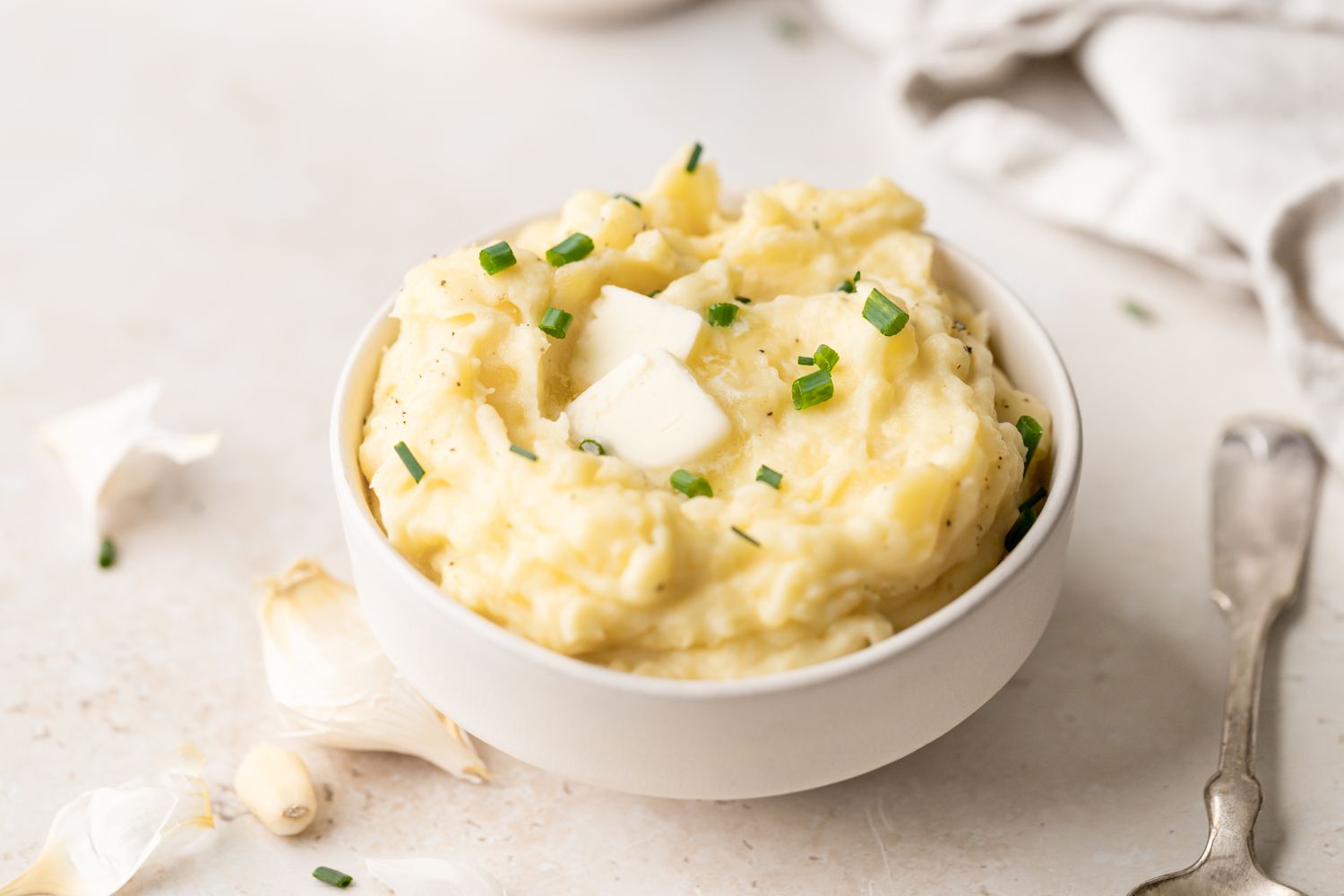 A bowl of roasted garlic mashed potatoes topped with a pat of butter.