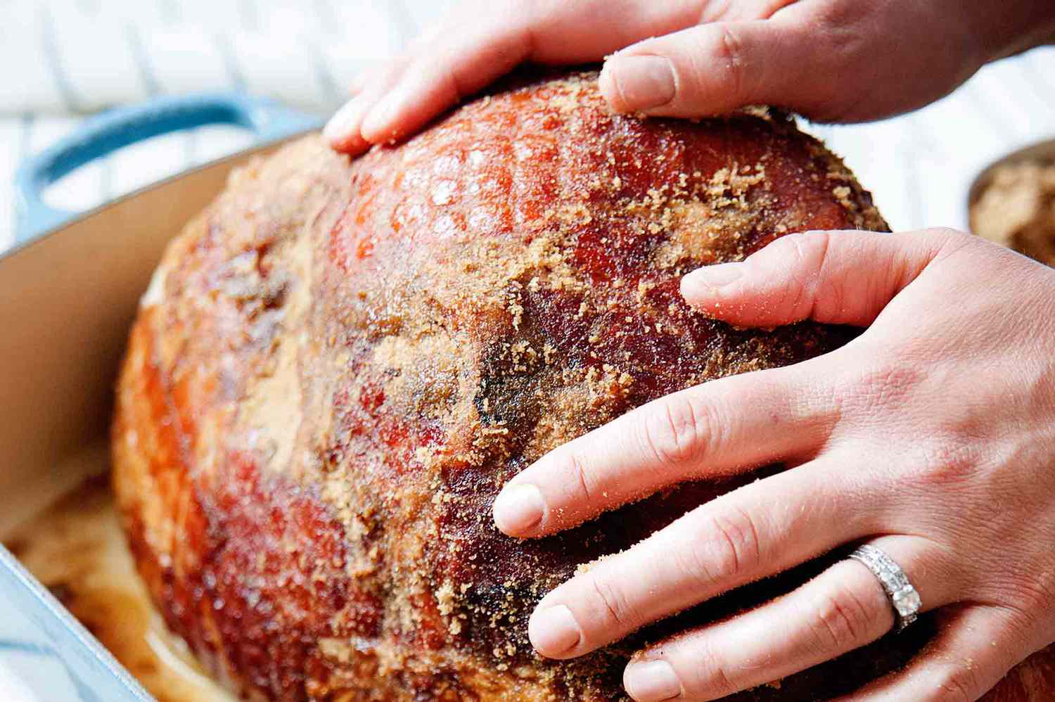 Glazed Ham with Brown Sugar - hands rubbing brown sugar into ham