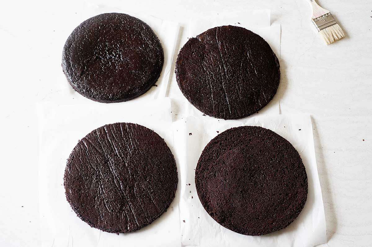 Four cake rounds set on parchment paper to make Homemade Black Forest Cake.