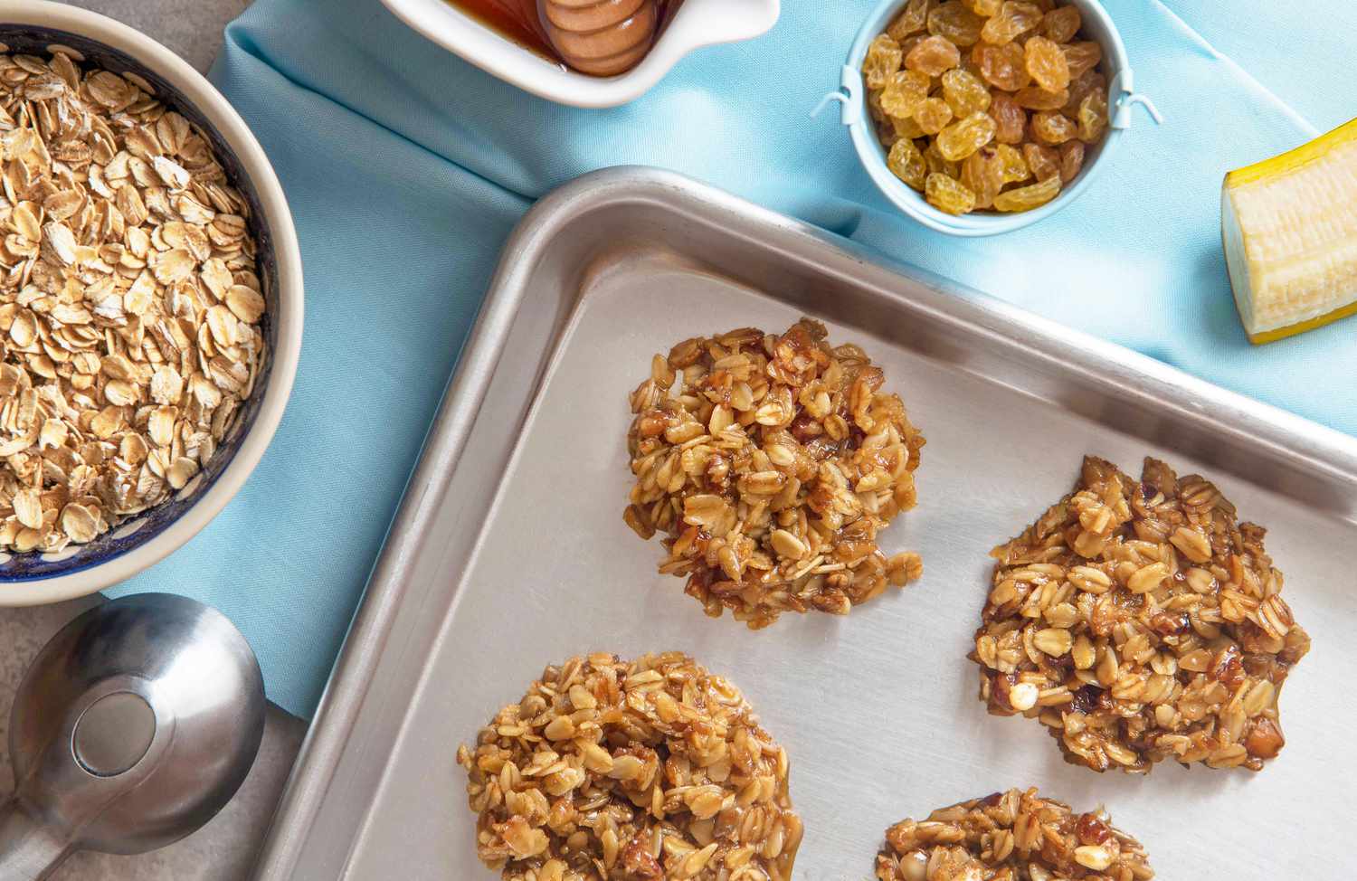 oatmeal raisin clusters on a baking pan next to a bowl of oats
