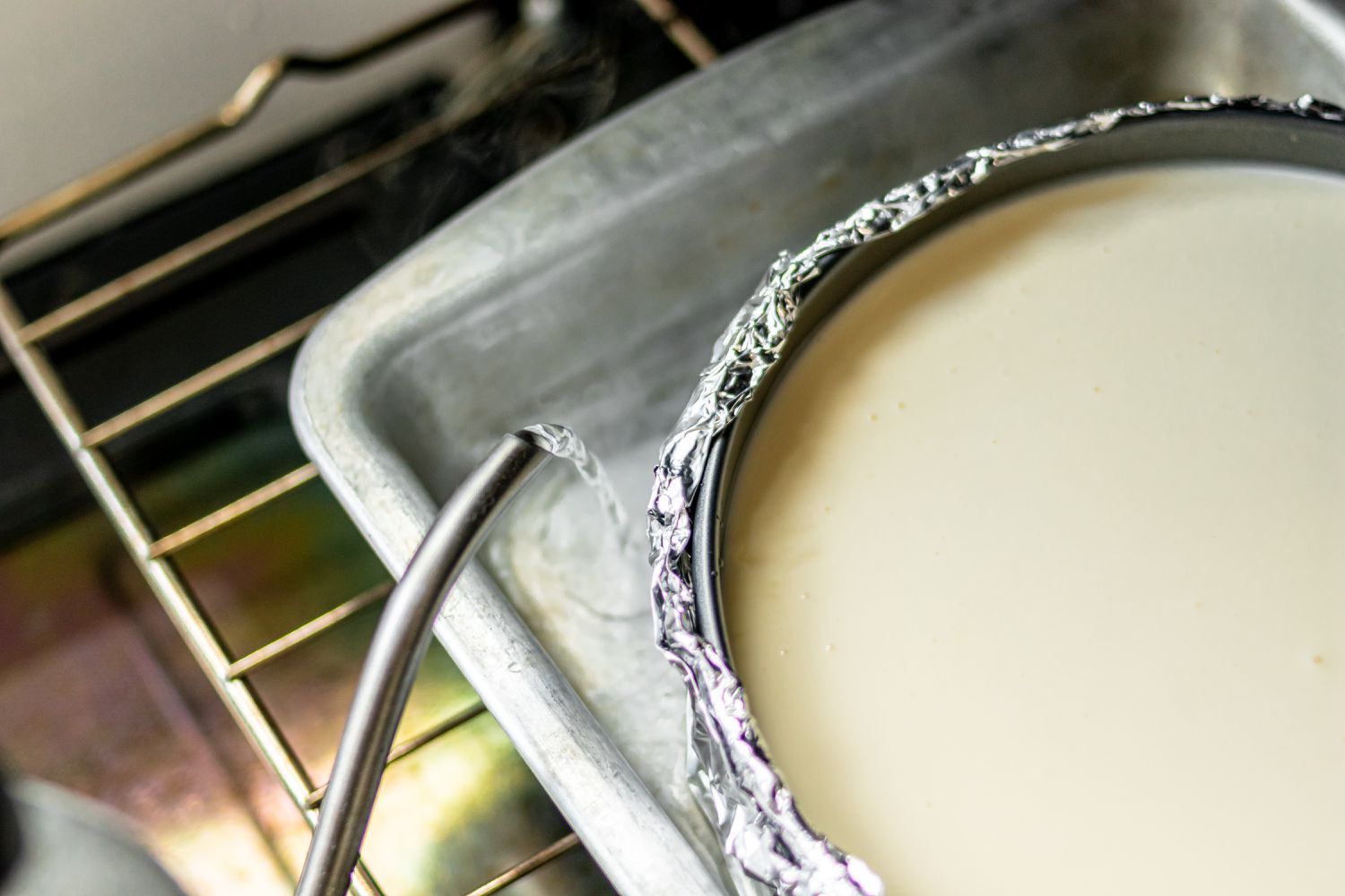 Filing the pan with water next to a baked cheesecake 