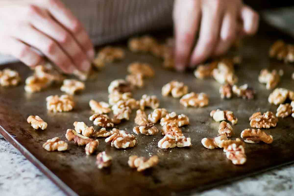 Walnuts being placed on a baking sheet
