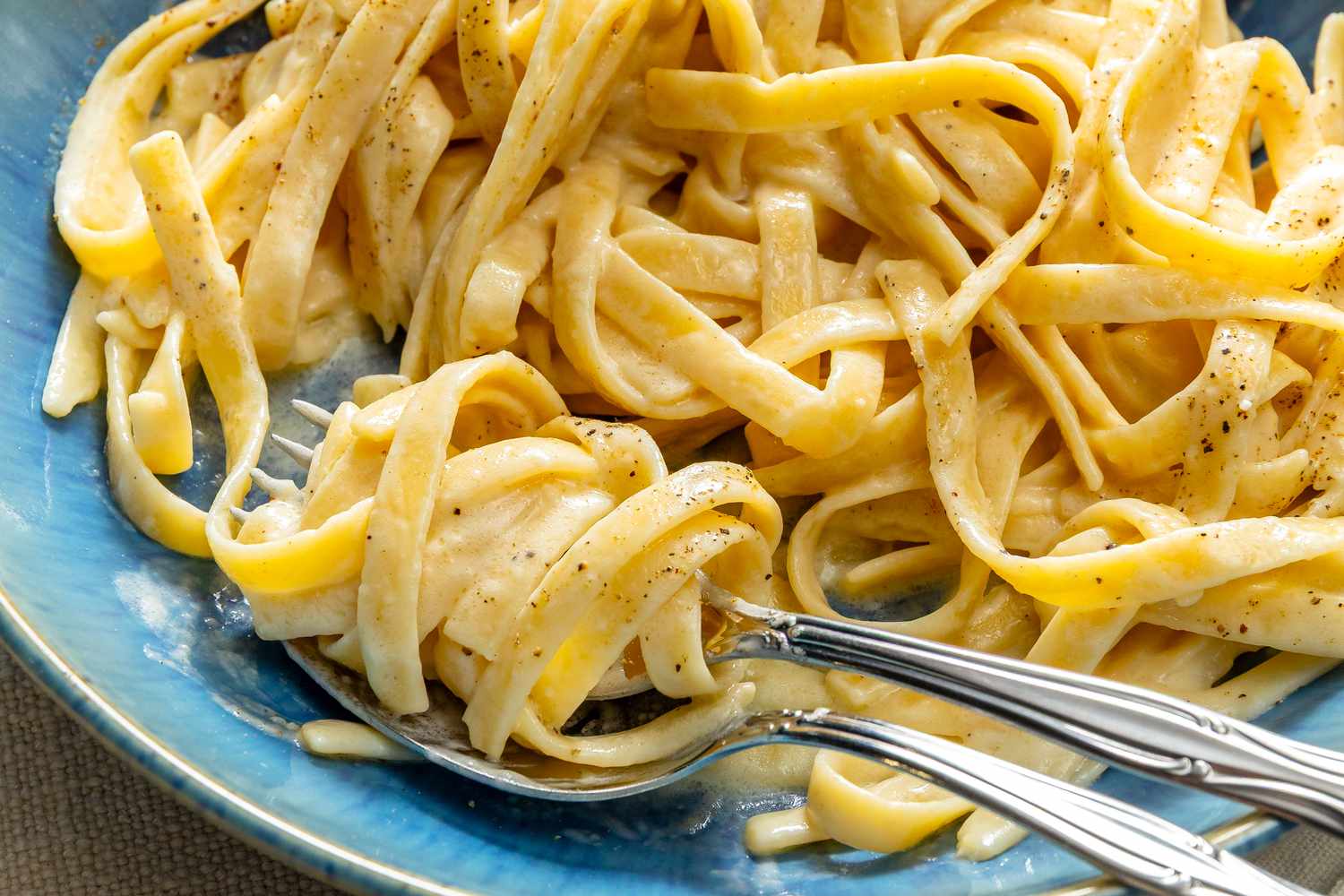 A plate of fettuccine alfredo with forks resting on it