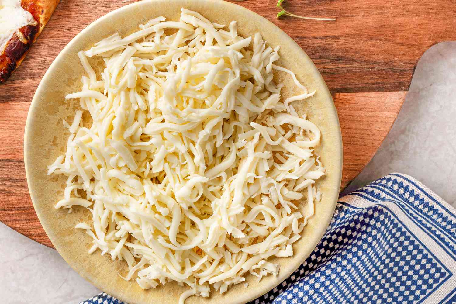 Plate of shredded mozzarella on a wooden surface