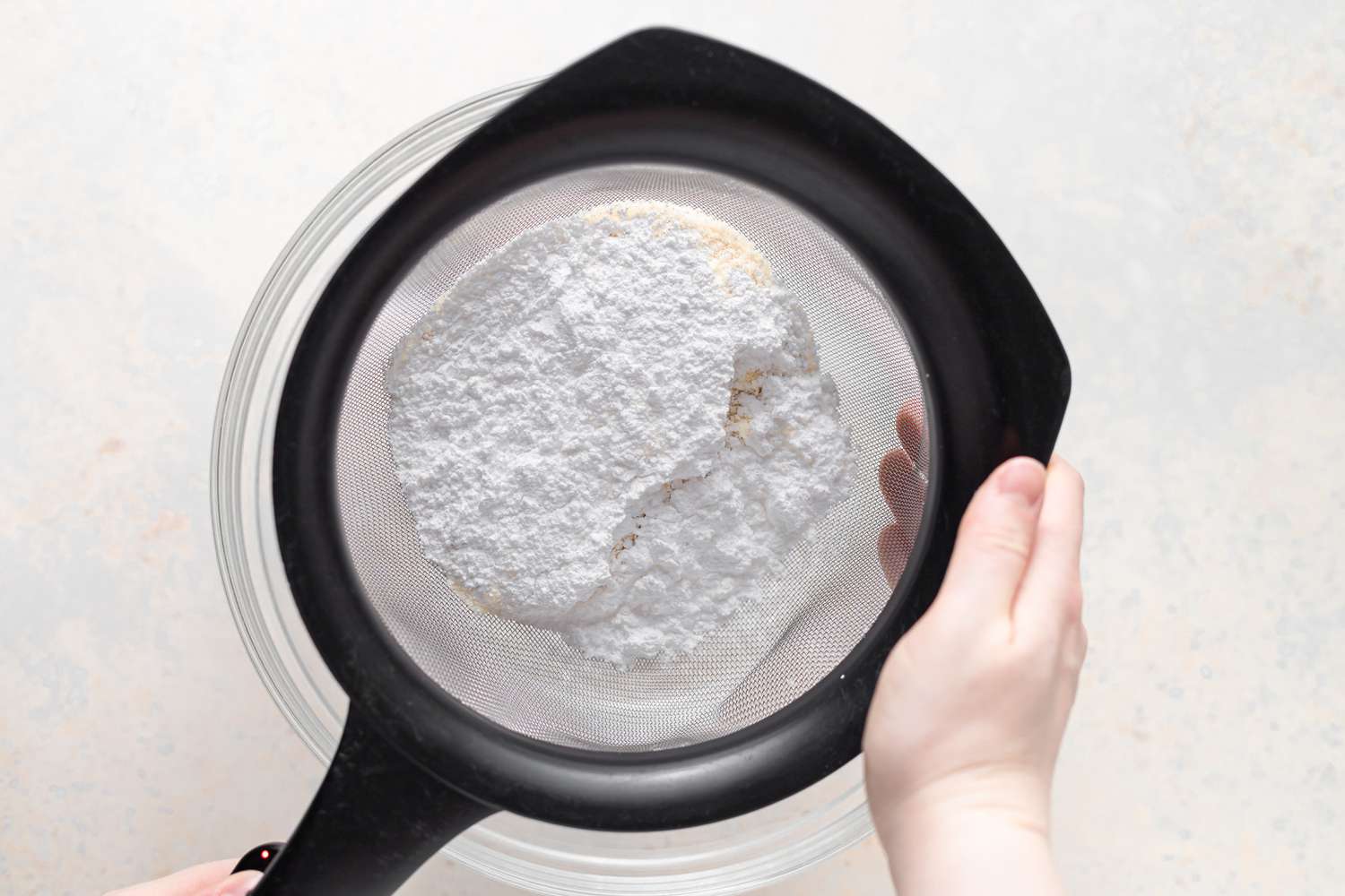 Sifting dry ingredients to make raspberry macarons filled with raspberry buttercream