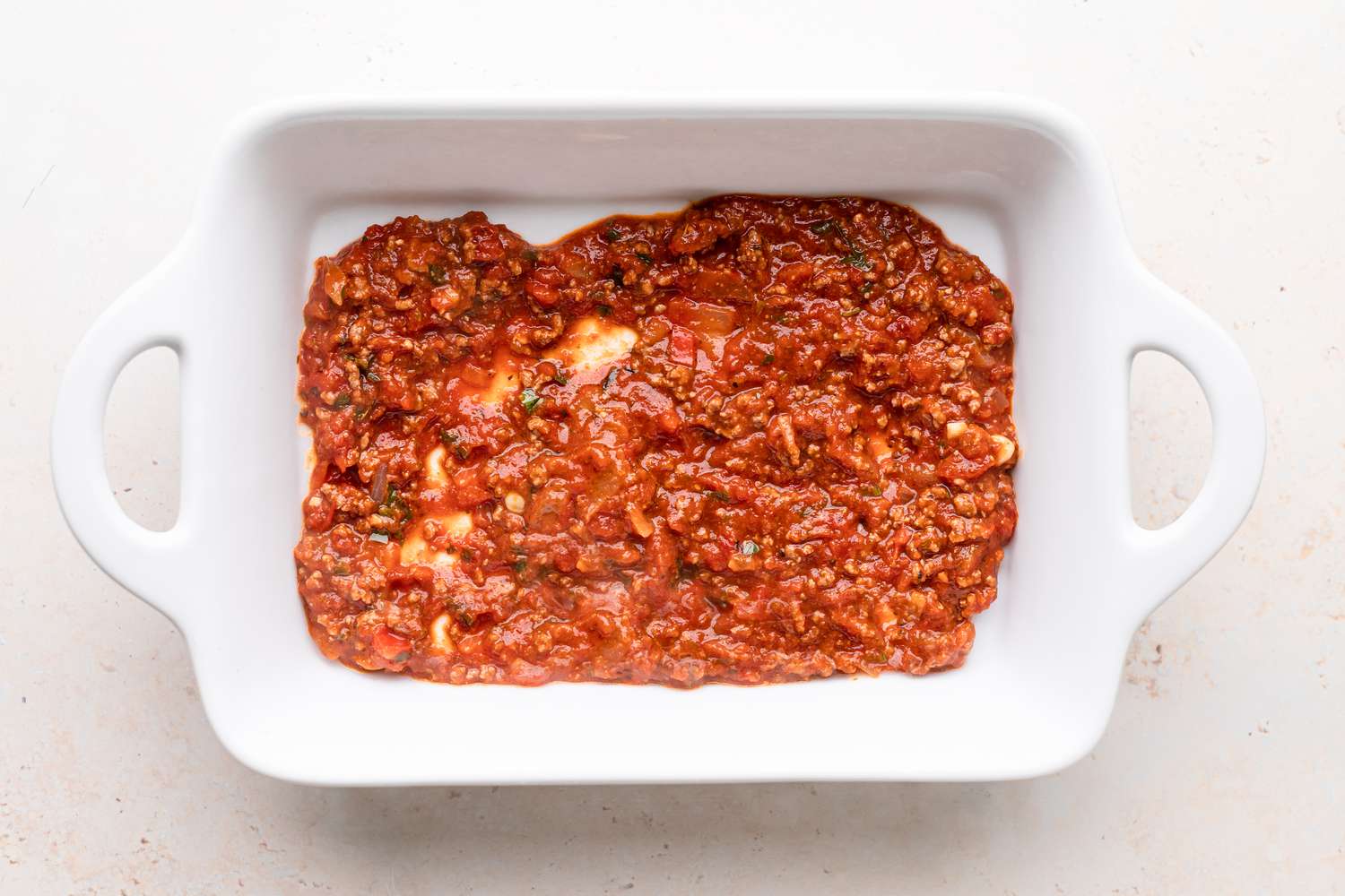 Sauce on the bottom of a pan to make the best lasagna recipe.