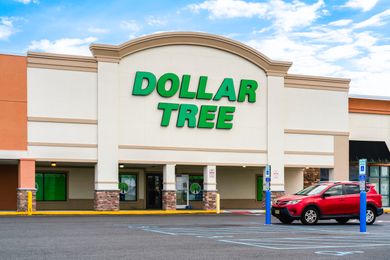 Storefront of a Dollar Tree location with a red car in the parking lot