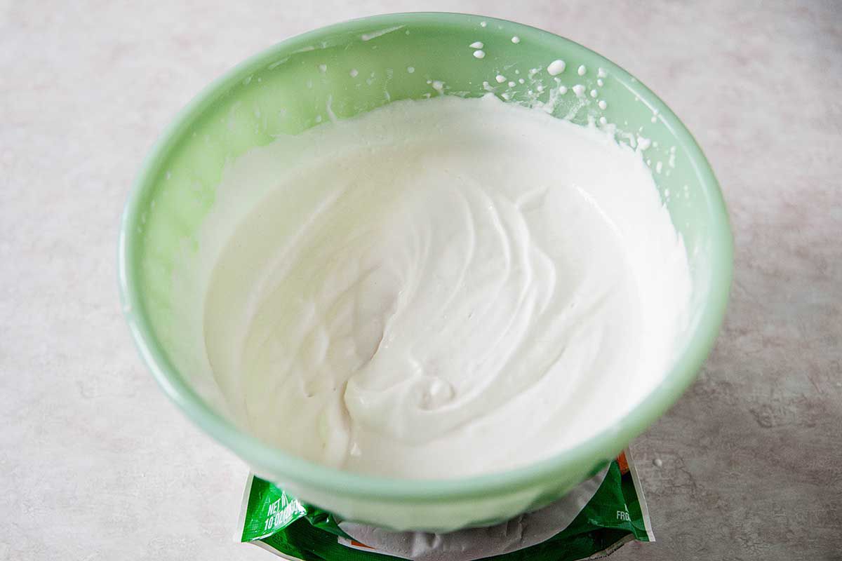 Homemade whipped cream in a mint green bowl.