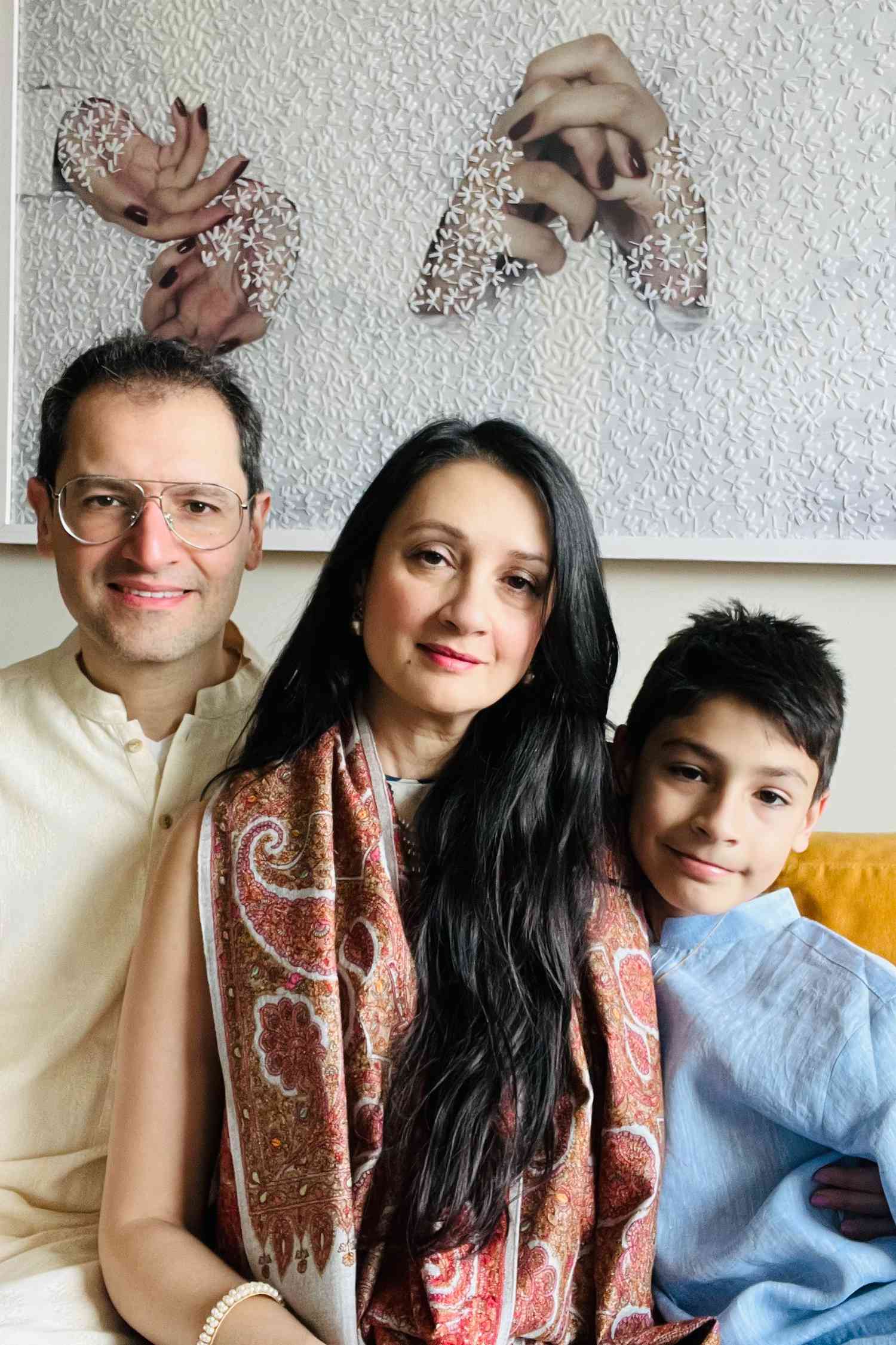 Family portrait of the author, her son, and her husband sitting on a bright yellow sofa