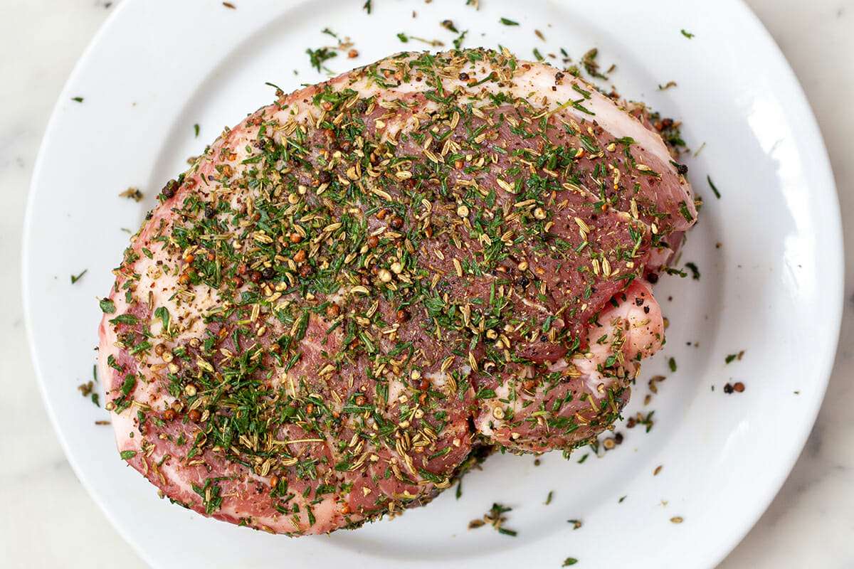 Pork roast recipe for oven with herbs and spices sprinkled over the top.